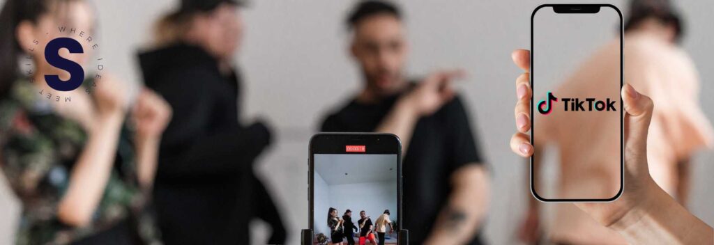 Imagen que muestra un grupo de jebenes haciendo una grabación y delante un montaje de un celular con el logo de TikTok.