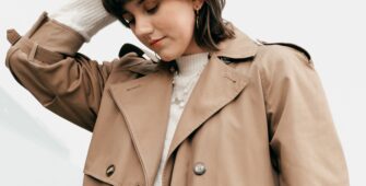 Mujer joven con cabello corto y chaqueta color Mocha Mousse, mirando hacia abajo con un fondo claro, representando los colores tendencia de 2025. A young woman with short hair and a Mocha Mousse-colored coat, looking down against a light background, representing the trend colors of 2025. Colores tendencia de 2025. Trend colors of 2025.