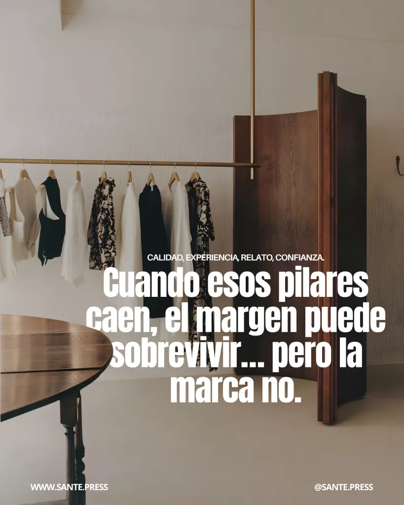 Interior minimalista de boutique con prendas neutras colgadas en perchas y mobiliario de madera, evocando lujo silencioso, calidad y posicionamiento de marca en moda contemporánea.