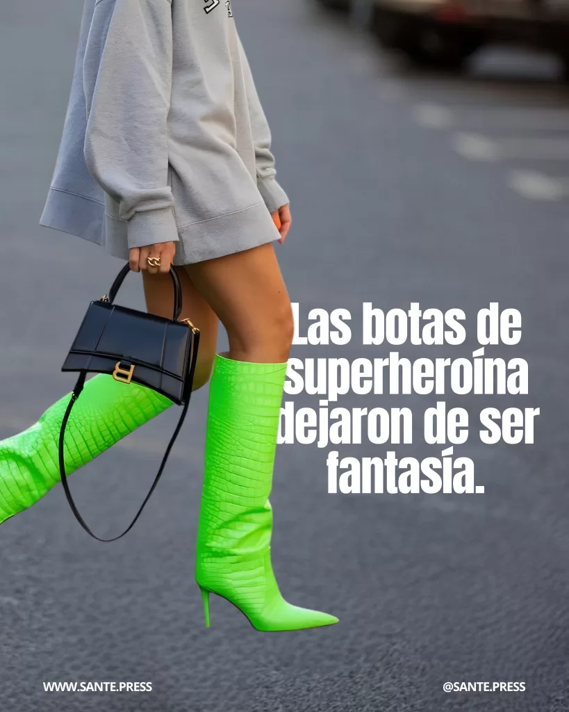 Primer plano de piernas con botas altas verde neón tipo reptil y tacón fino, combinadas con sudadera gris y bolso negro estructurado