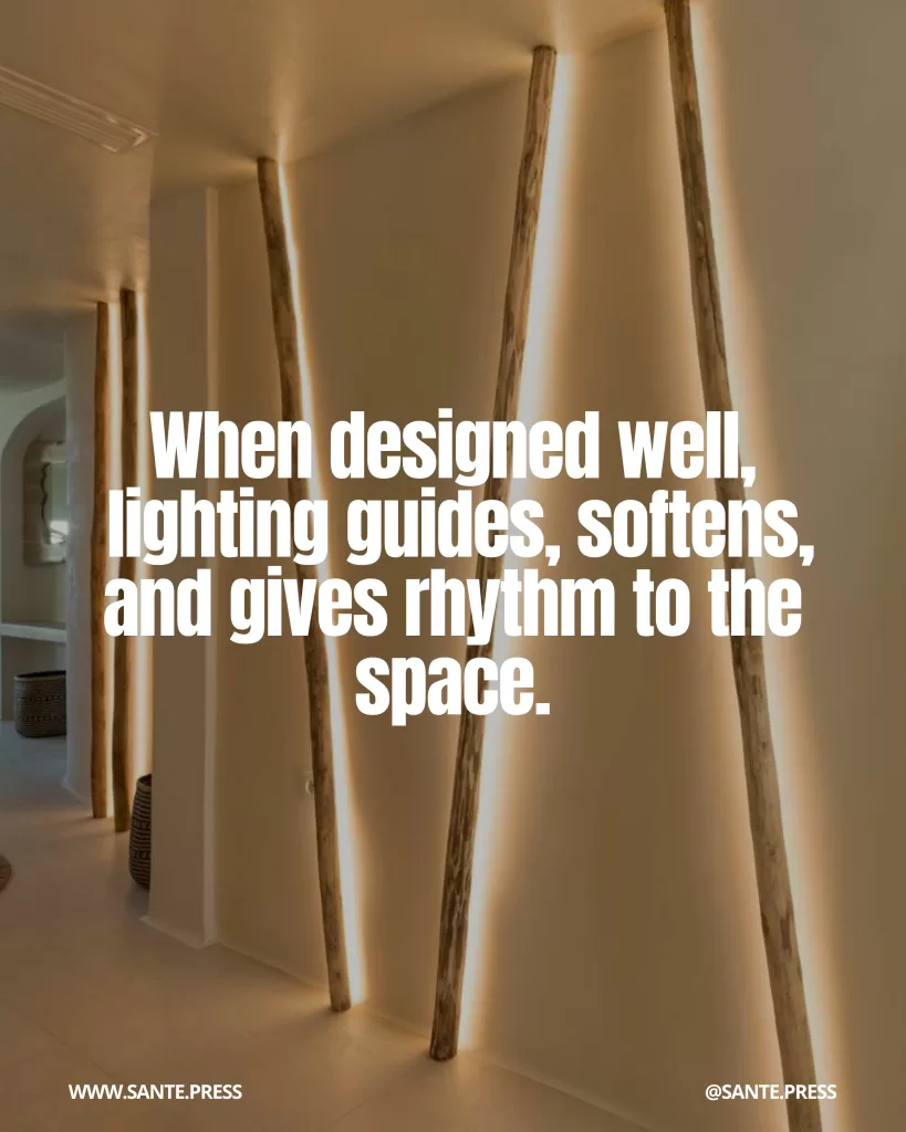 Pasillo interior con iluminación arquitectónica integrada detrás de elementos verticales de madera que crean líneas de luz cálida en la pared. Texto: “When designed well, lighting guides, softens, and gives rhythm to the space.”